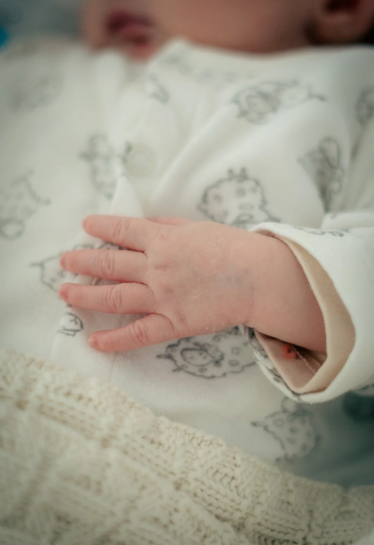 Eine kleine Babyhand auf einer weichen Decke