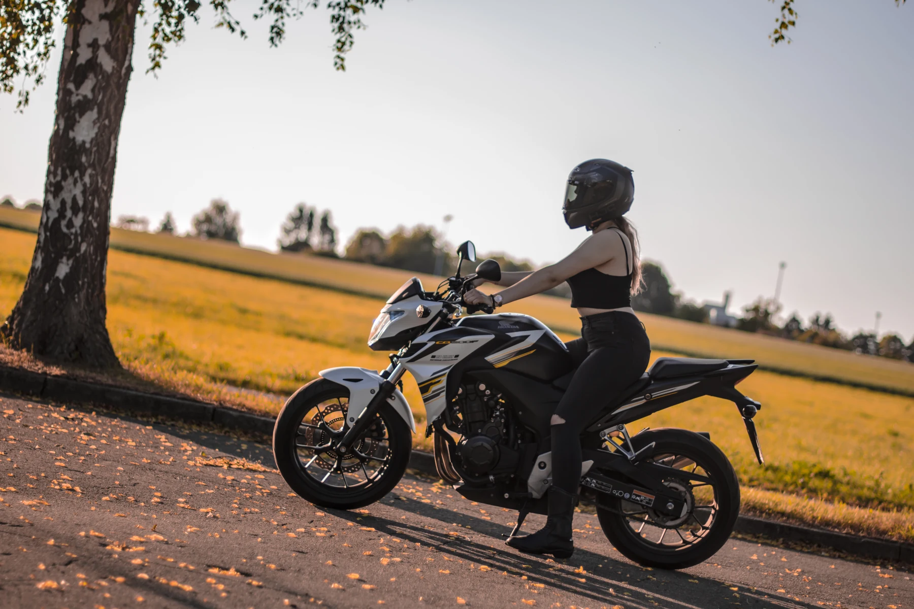 Melanie mit Motorrad an einer Baumreihe
